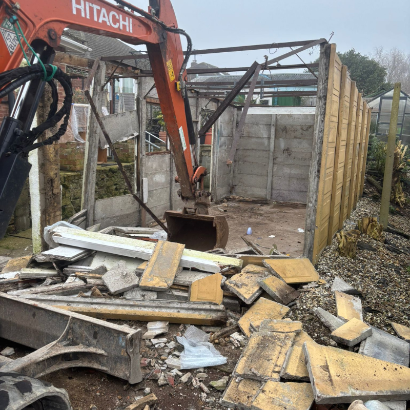 Digger dismantling a concrete garage
